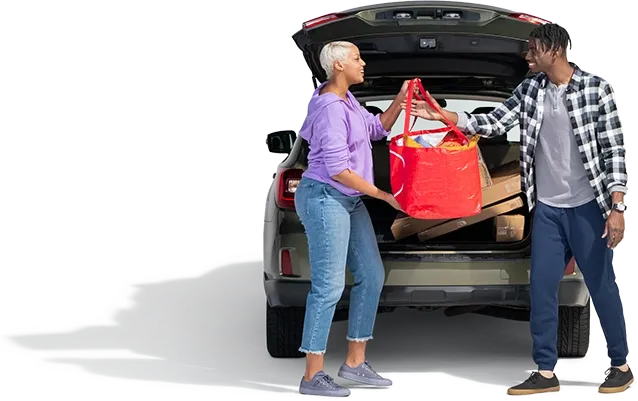 A mom hands a red grocery bag to her son happy she combined their home and auto policies to save money.